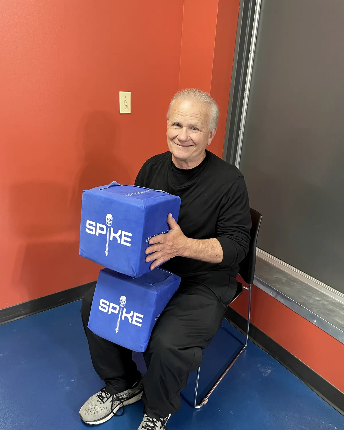 An older man holding two SPIKE blocks