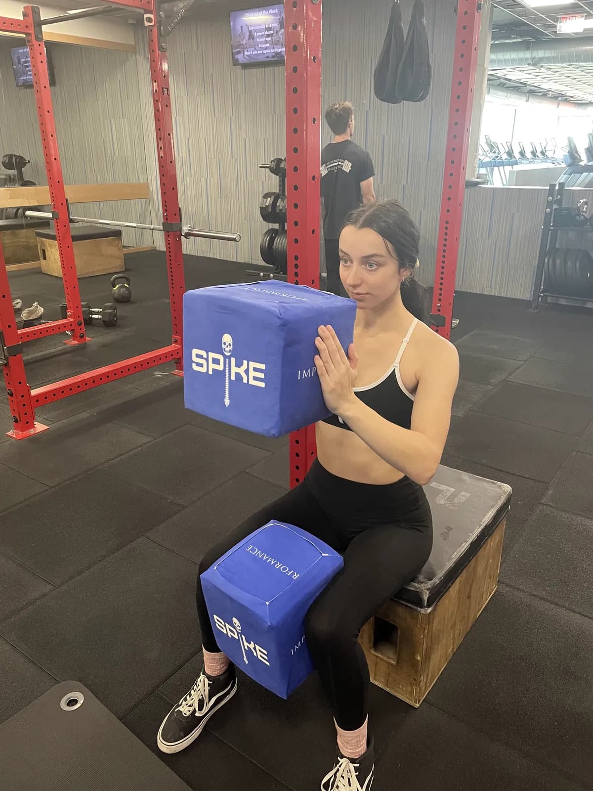 A woman holding a SPIKE position in a squat rack